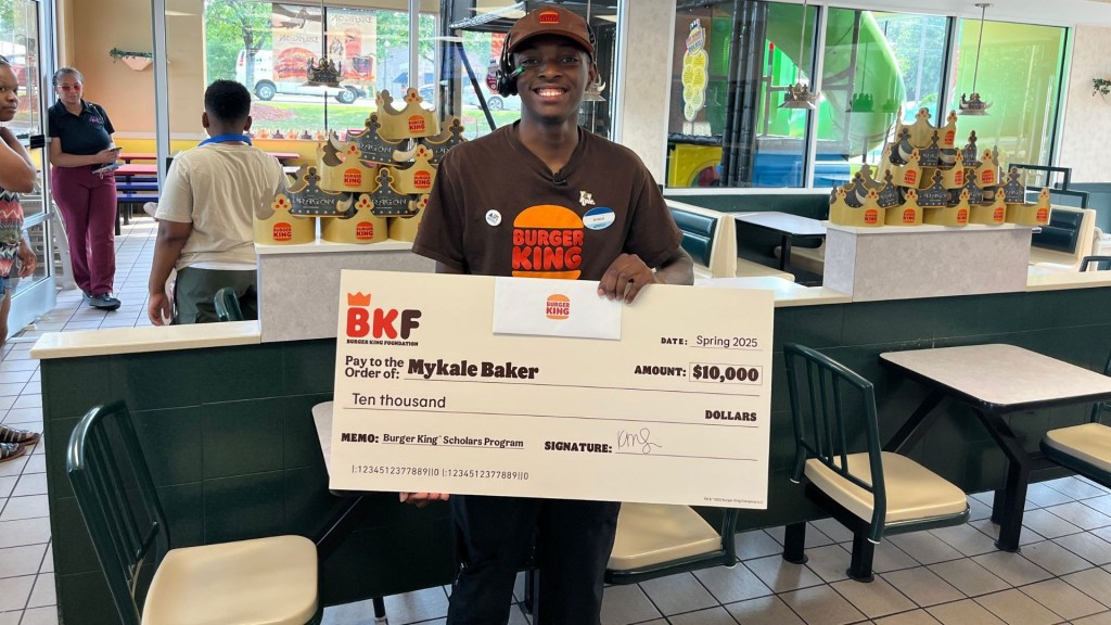 Mykale Baker, Burger King employee, holding a $10,000 scholarship check.