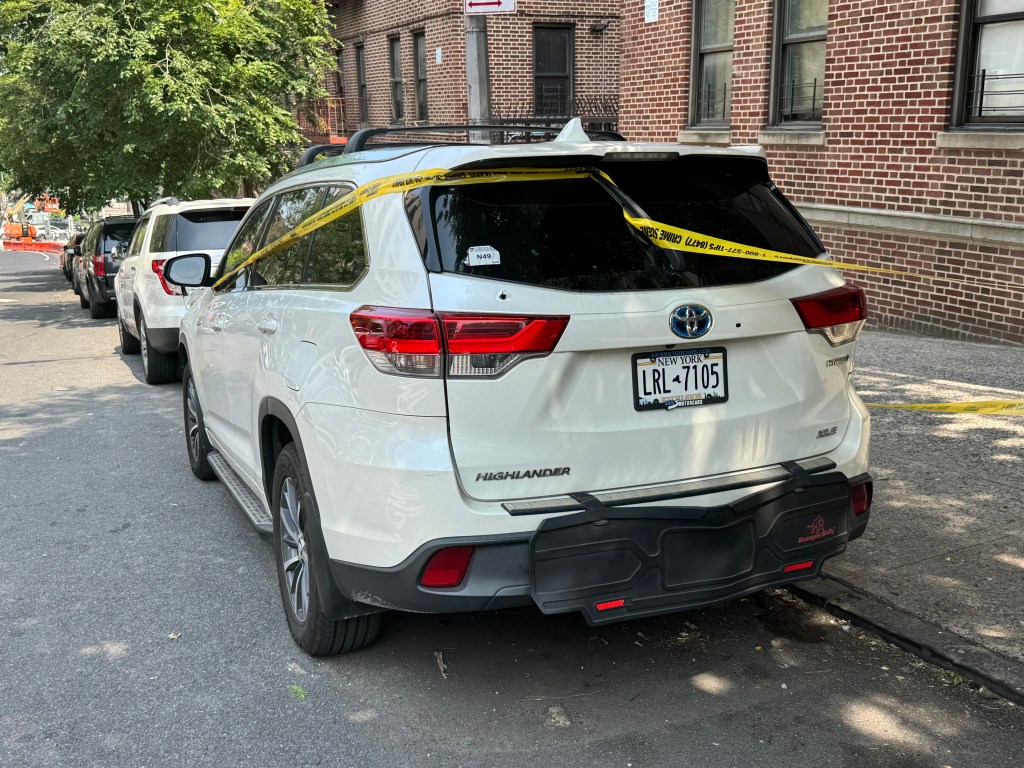 White SUV with police tape at a crime scene.