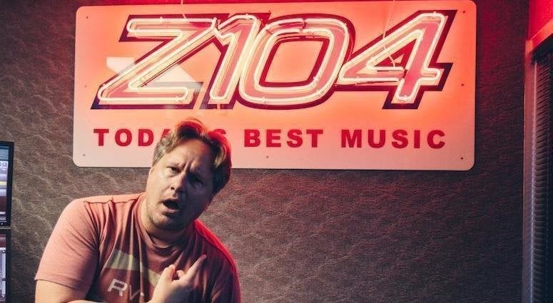 Man in front of Z104 radio station sign.