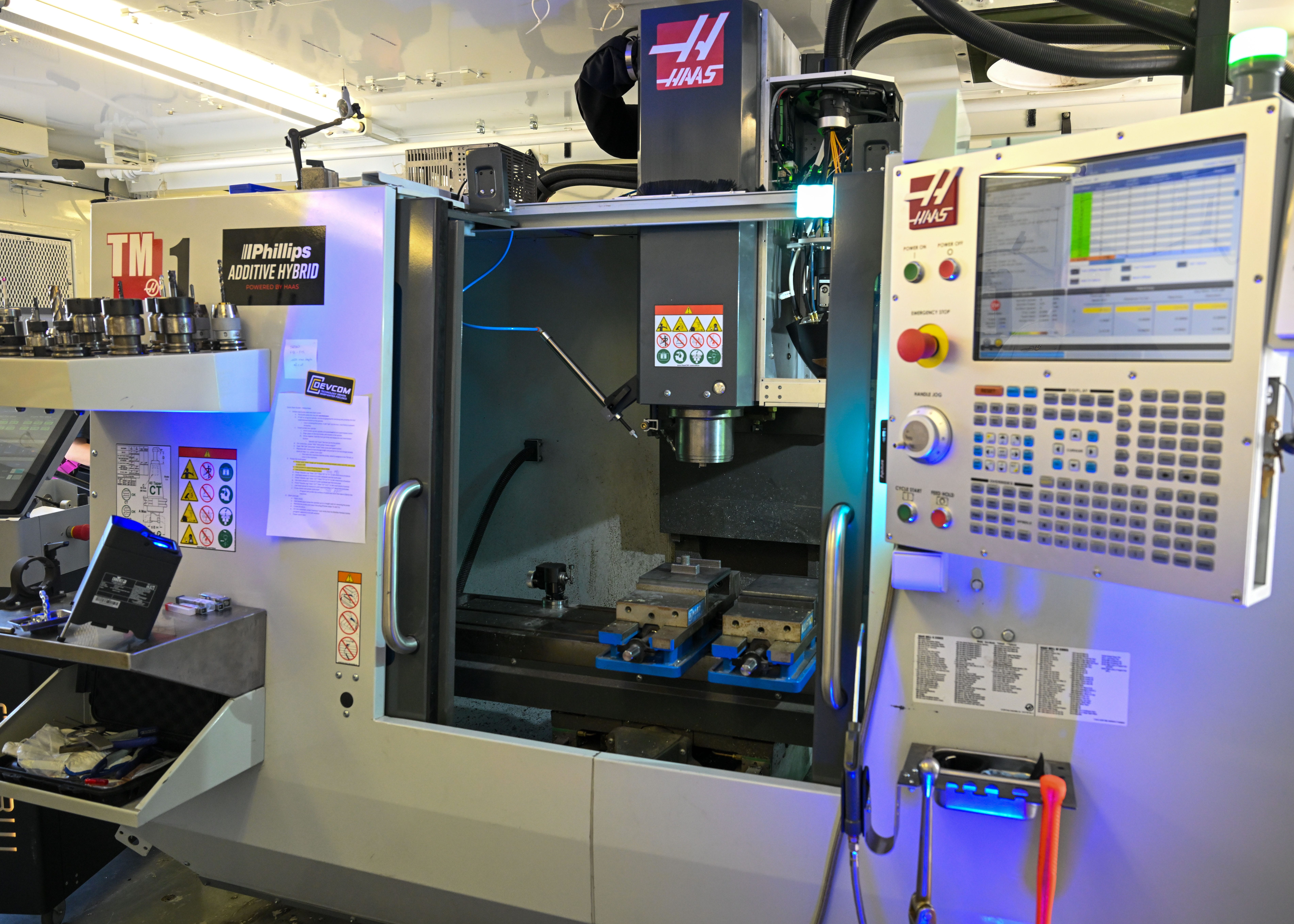 A white manufacturing machine is seen, with various buttons, parts, and screens.