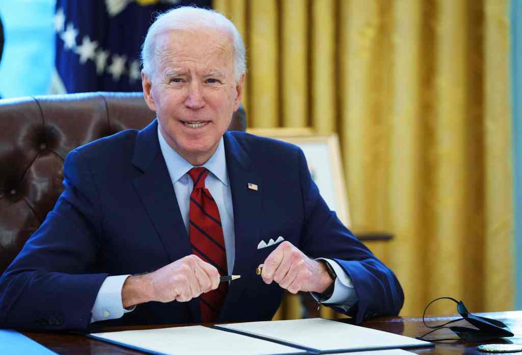 President Biden signing executive orders in the Oval Office.