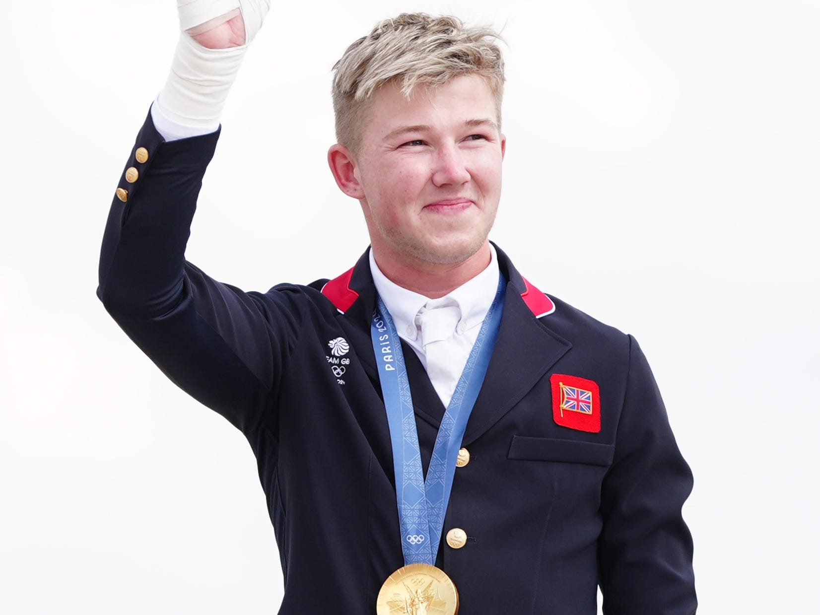 Harry Charles waves with an Olympic gold medal around his neck.