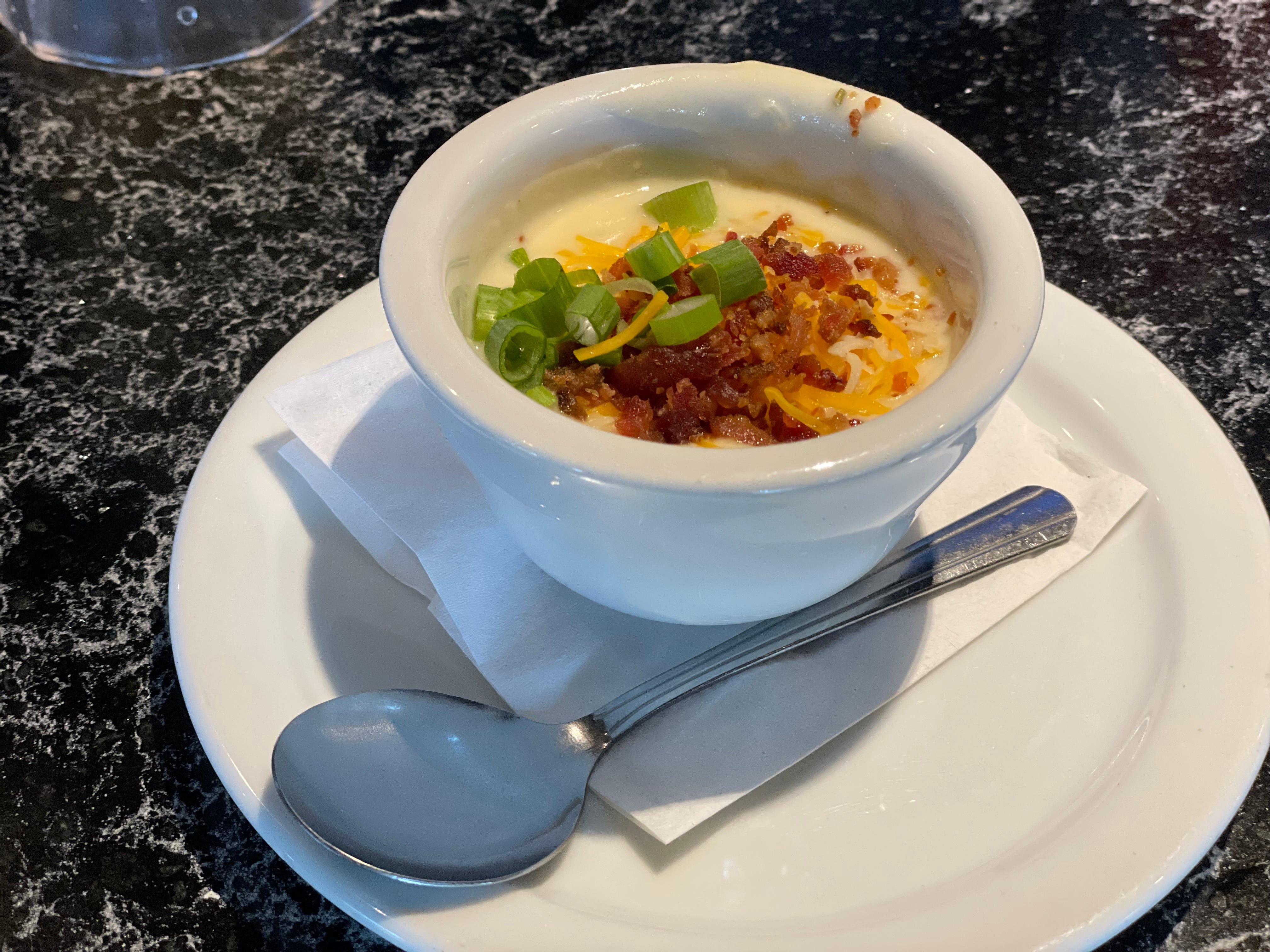 Bowl of loaded baked potato soup topped with bacon bits, cheese, green onion at chili's