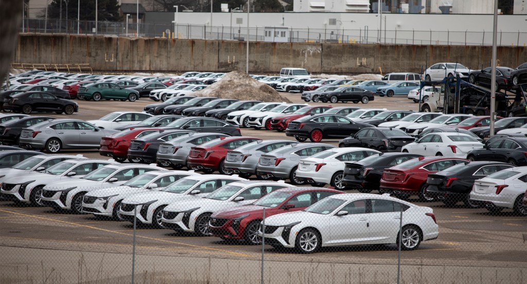 Numerous new Cadillacs parked in a lot.