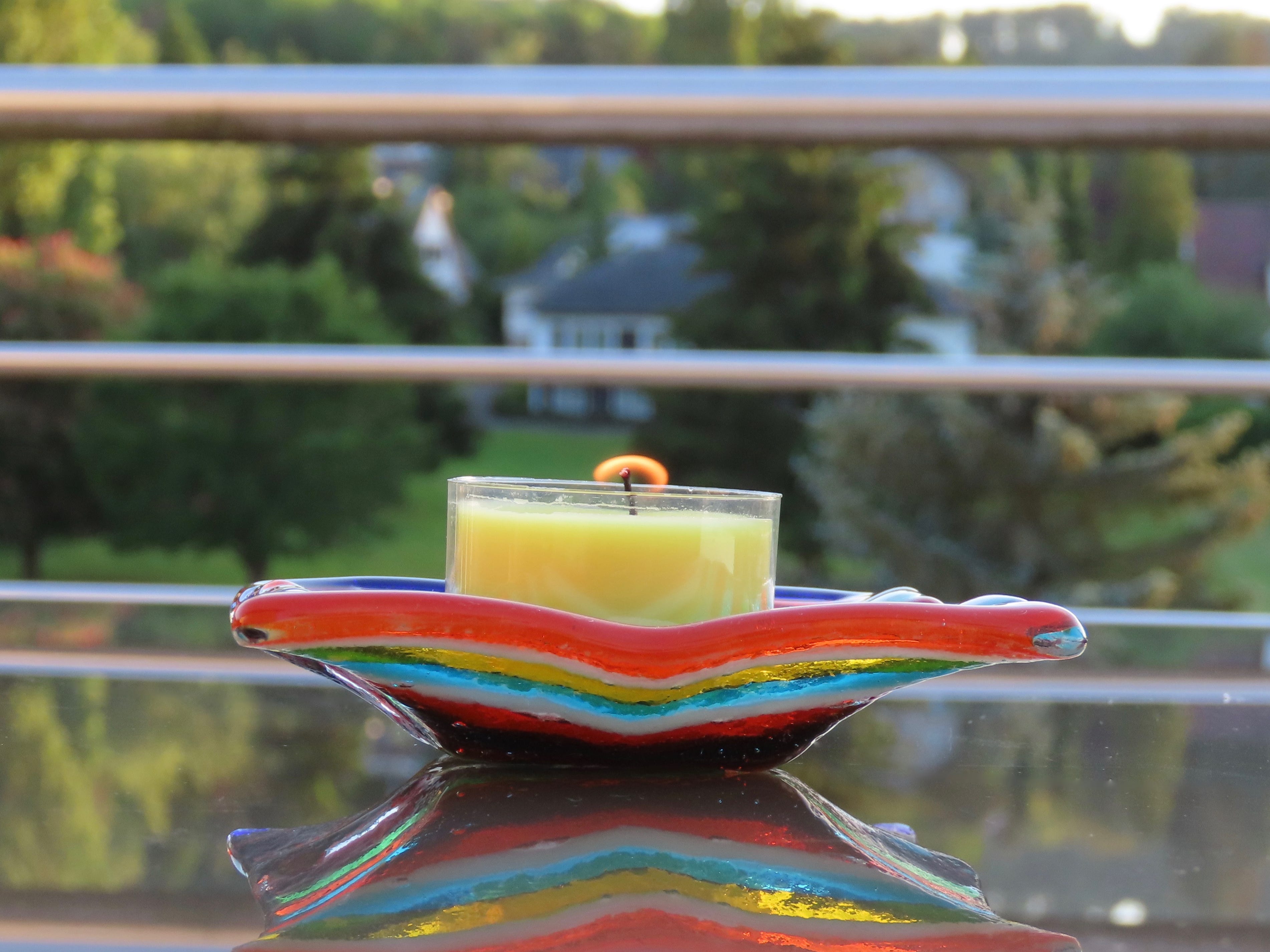lit citronella candle ina. colorful blown glass dish