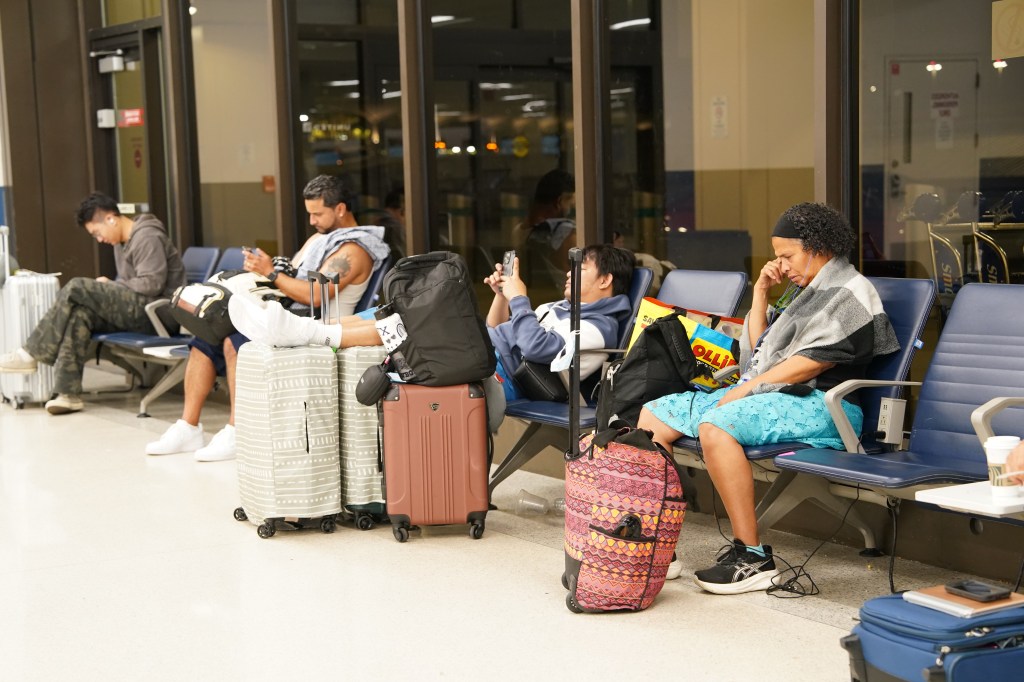 Passengers waiting at an airport gate with luggage.