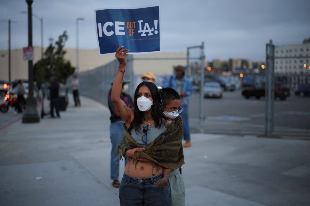 A demonstrator holds a placard as protesters gather around the Los Angeles Federal Building.