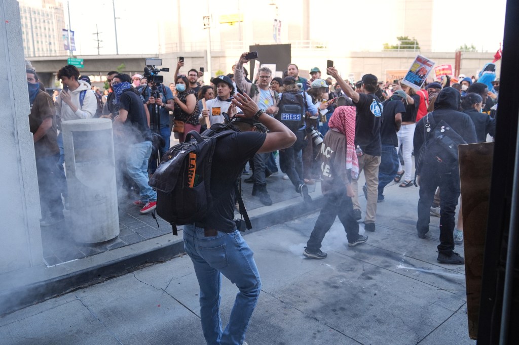 Person shielding their head from pepper spray during a protest in Los Angeles.