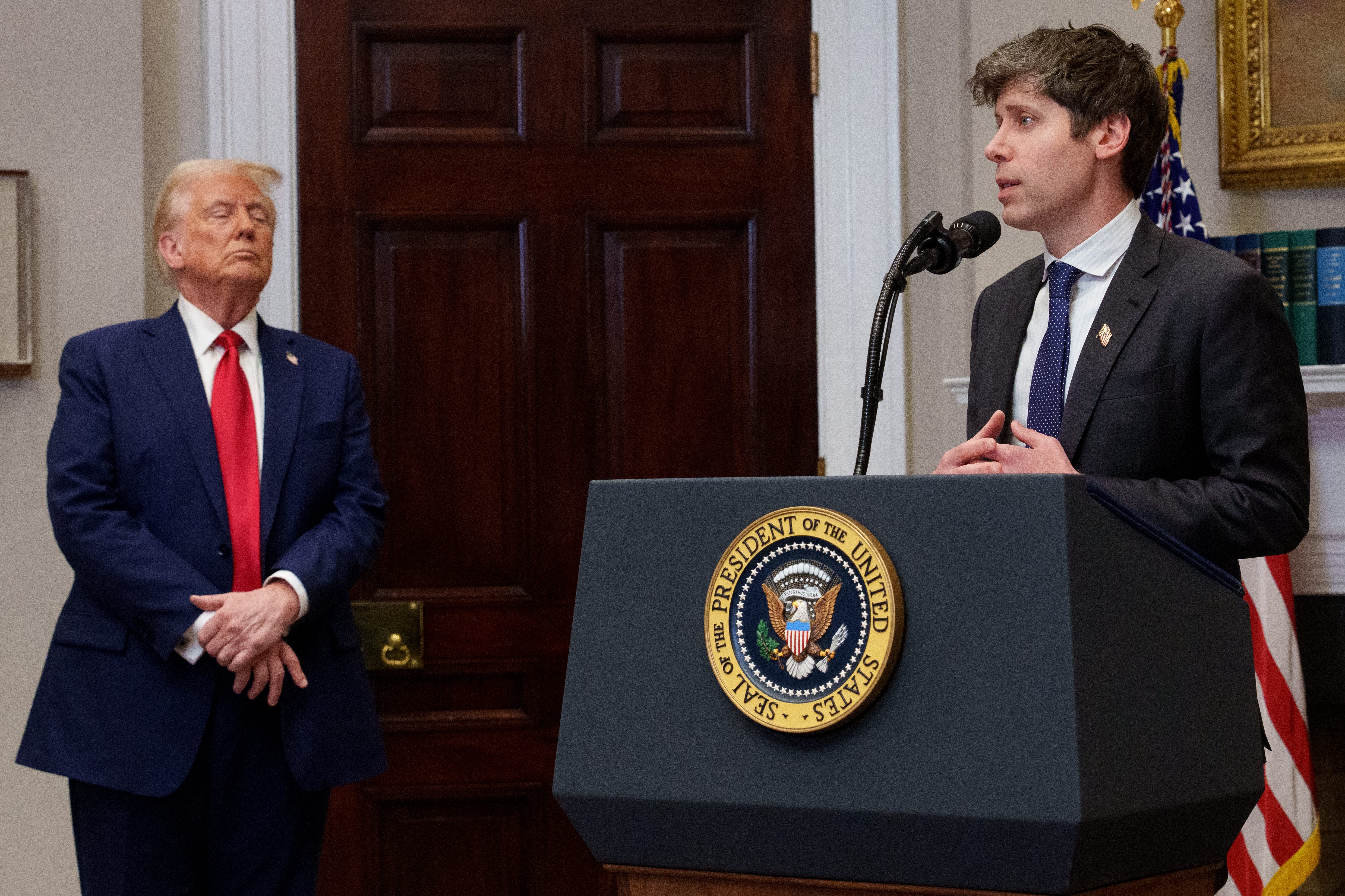 President Donald Trump looking toward OpenAI CEO Sam Altman, as Altman speaks to reporters at the White House.