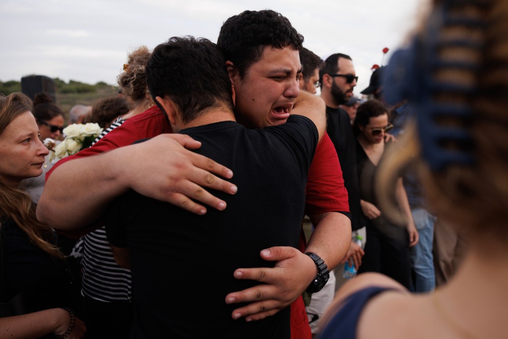 Mourners embrace at a funeral.