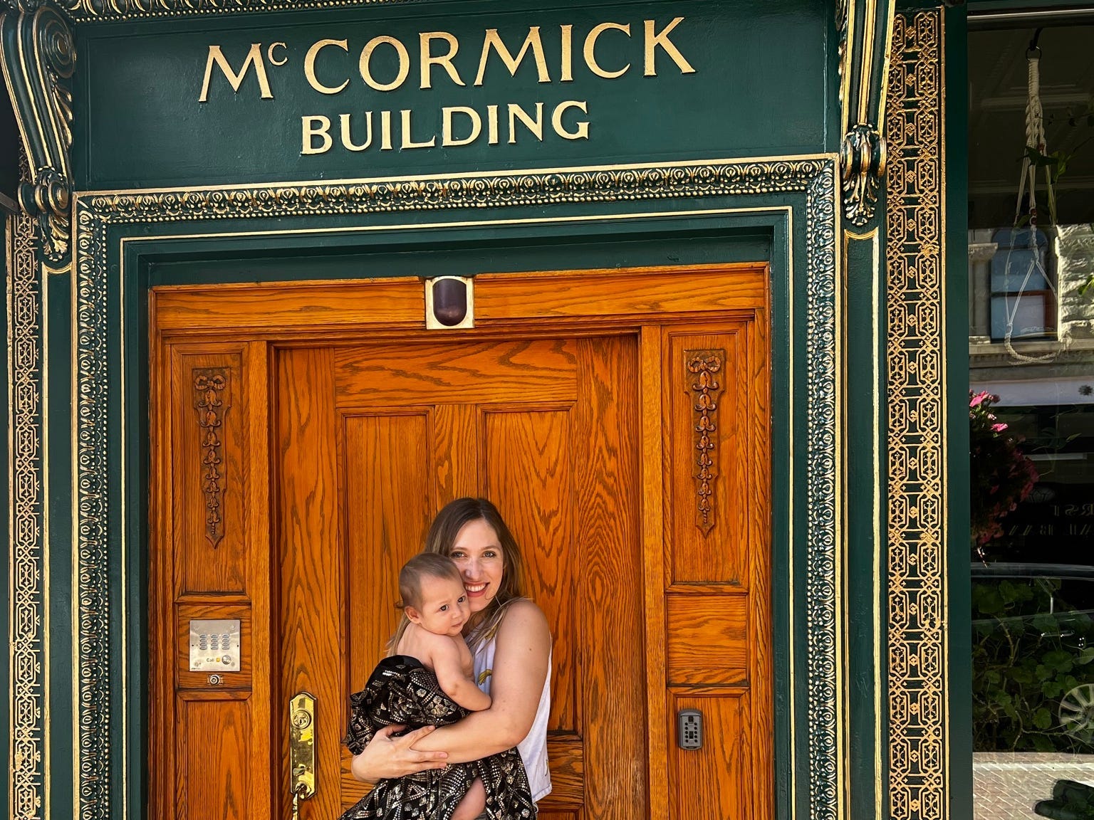 The author and her youngest child standing in front of the McCormick Building's wooden doors before a literary event.