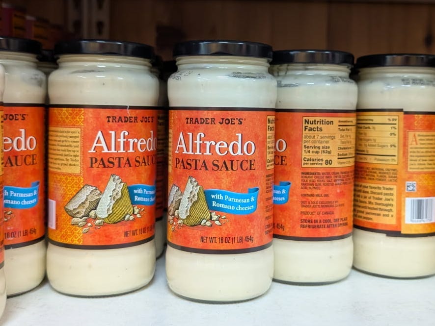 Jars of Alfredo pasta sauce on the shelf at Trader Joe's.