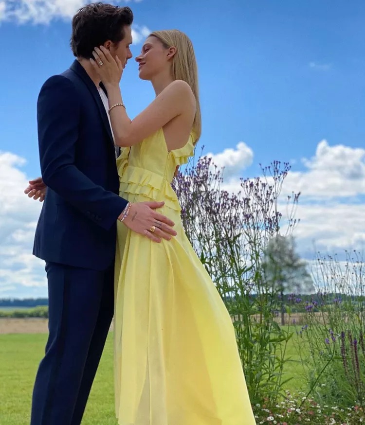 Brooklyn Beckham, in a black suit, hugs Nicola Peltz Beckham in a yellow dress.