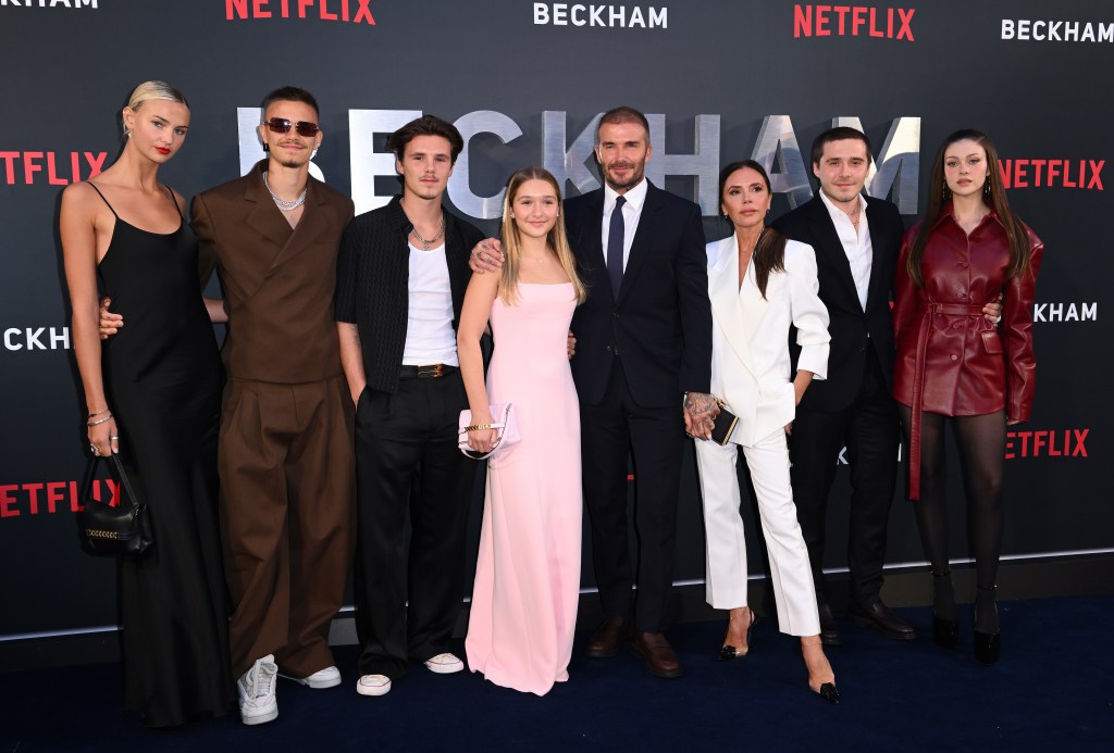 Mia Regan in a black dress, Romeo Beckham in a brown suit and white sneakers, Cruz Beckham in a black shirt, white t-shirt and black pants, Harper Beckham in a pink gown, David Beckham in a black suit, white shirt and dark tie, Victoria Beckham in a white pant suit, Brooklyn Beckham in a black suit and white shirt, Nicola Peltz Beckham in a brown leather jacket and dark tights.