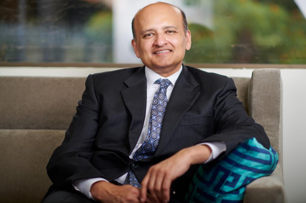 Dr. Amit Kumar in a suit sitting on a couch for a photo