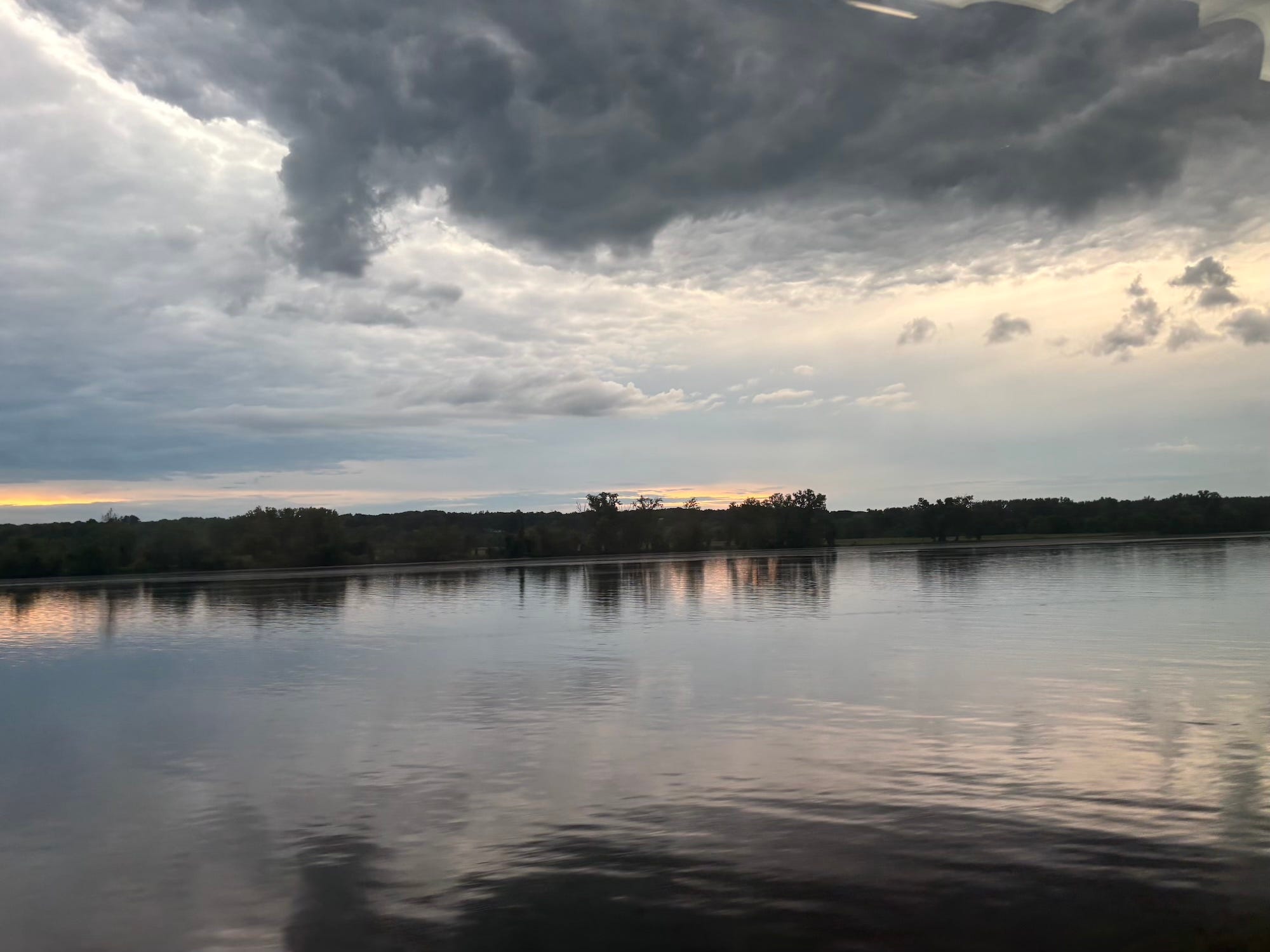 A lake surrounded by trees with clouds in the sky.