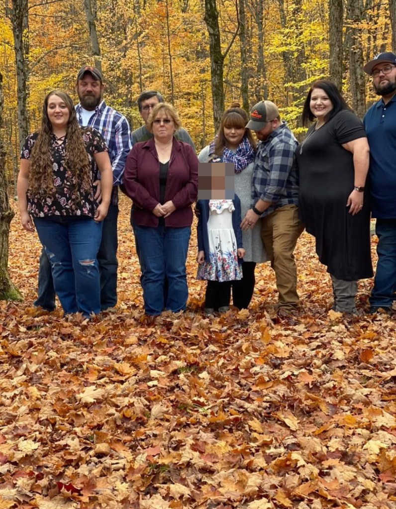family photo posted to Facebook by Joyce Mitchell shows her and husband Lyle posing in a forest among six other adults and a small blonde girl