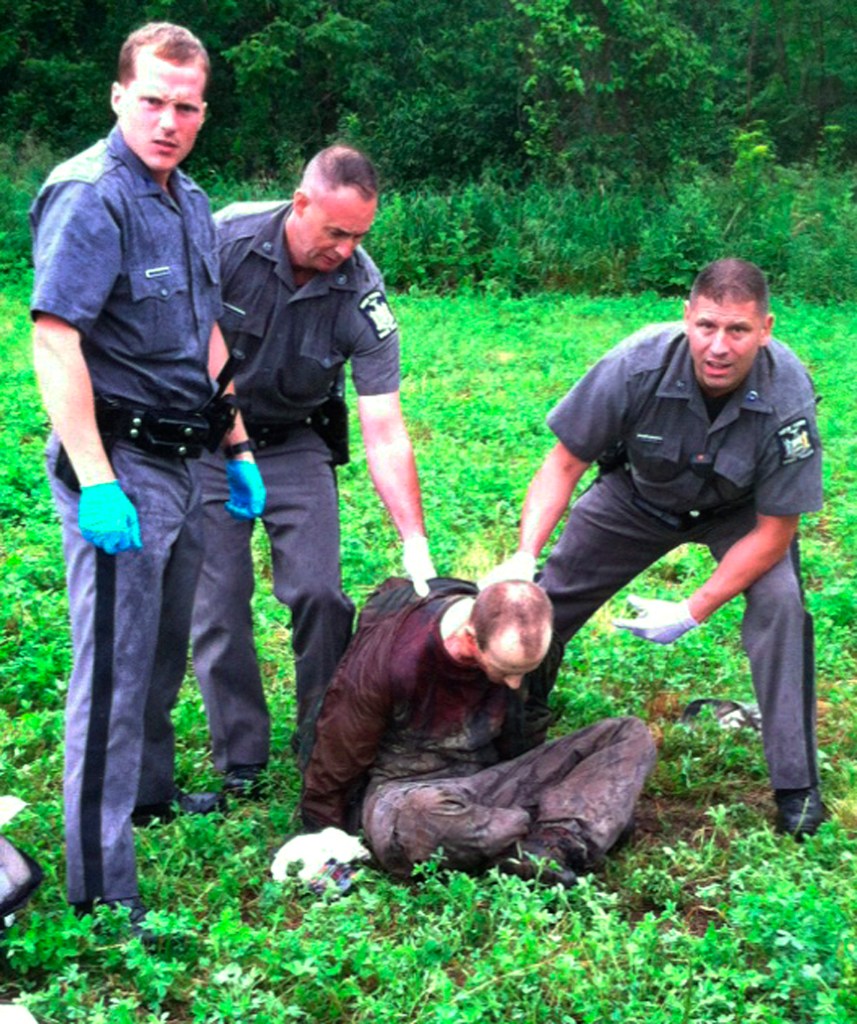 Police stand over David Sweat after he was shot and captured near the Canadian border Sunday, June 28, 2015, in Constable, N.Y.