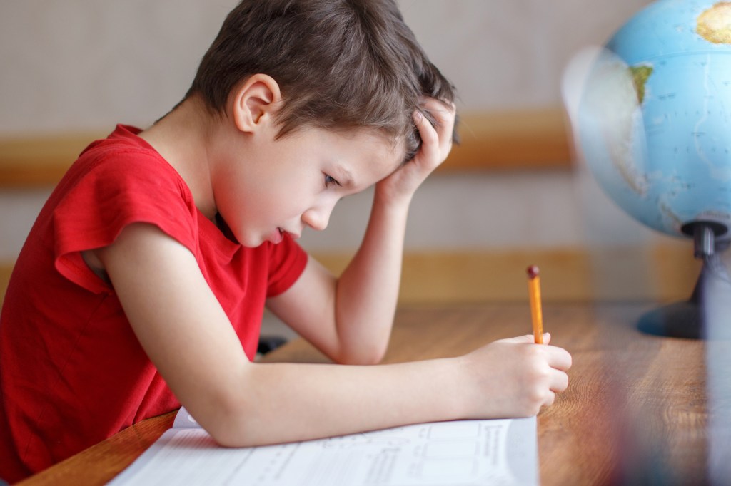 A sad young boy struggling with his homework.