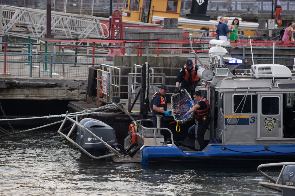 Police officers loading a body onto a boat. 