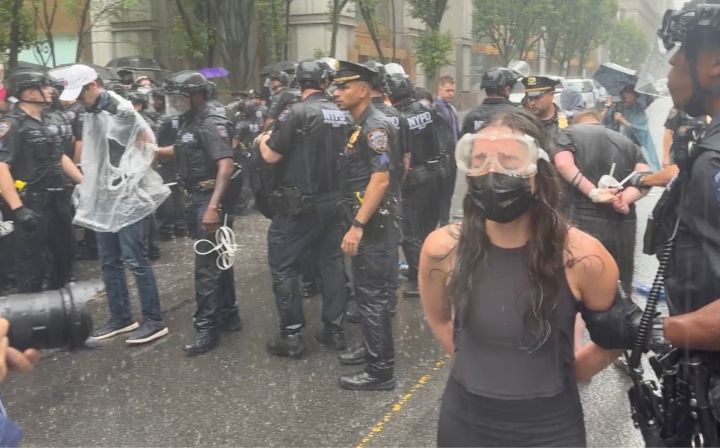 woman wearing face mask and goggles seen crying while getting arrested at the protest in front of 26 Federal Plaza on Saturday, June 7, 2025