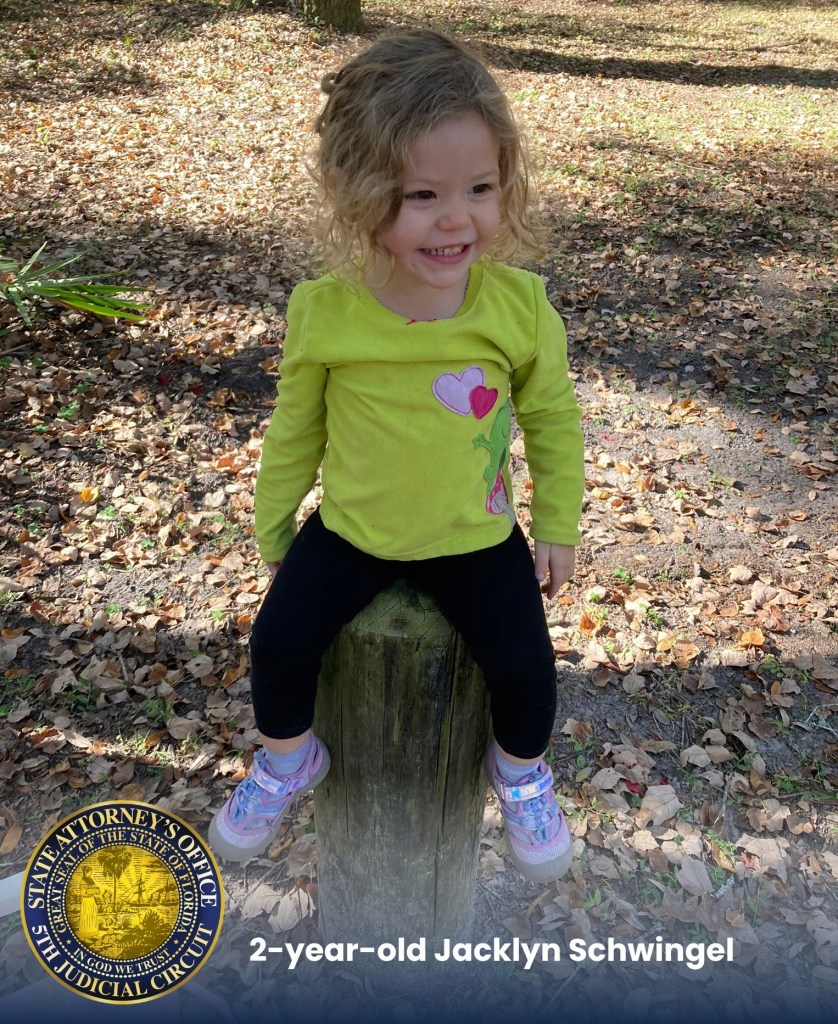 Photo of Jacklyn Schwingel, a 2-year-old girl smiling and sitting on a wooden pole