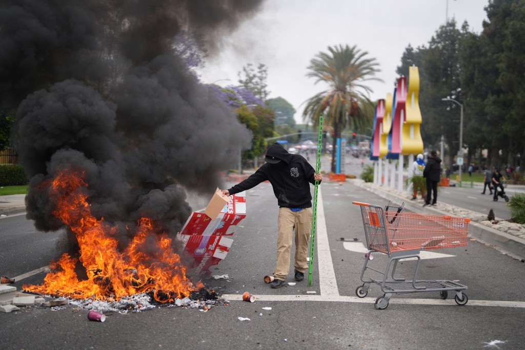 A protester adds fuel to a fire during an immigration raid in Los Angeles.