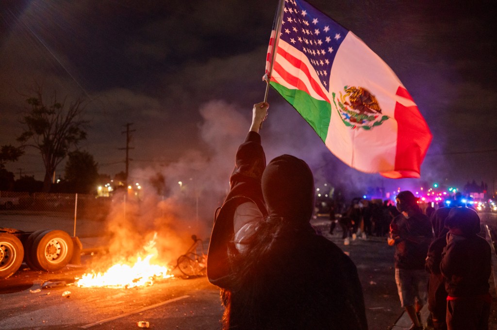 A protester aves a flag in front of a fire set in the middle of the street in the Compton neighborhood of Los Angeles.