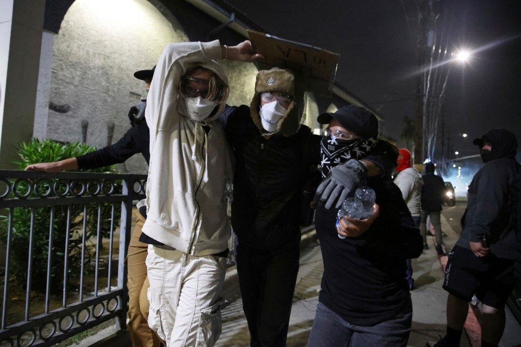Masked protesters wearing safety goggles move away from law enforcement agents in Compton, Calif.
