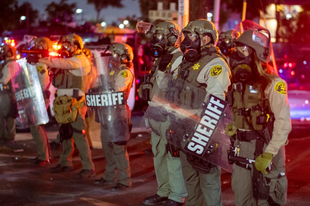 Los Angeles County Sheriff's deputies form a line in riot gear during a standoff with protesters.