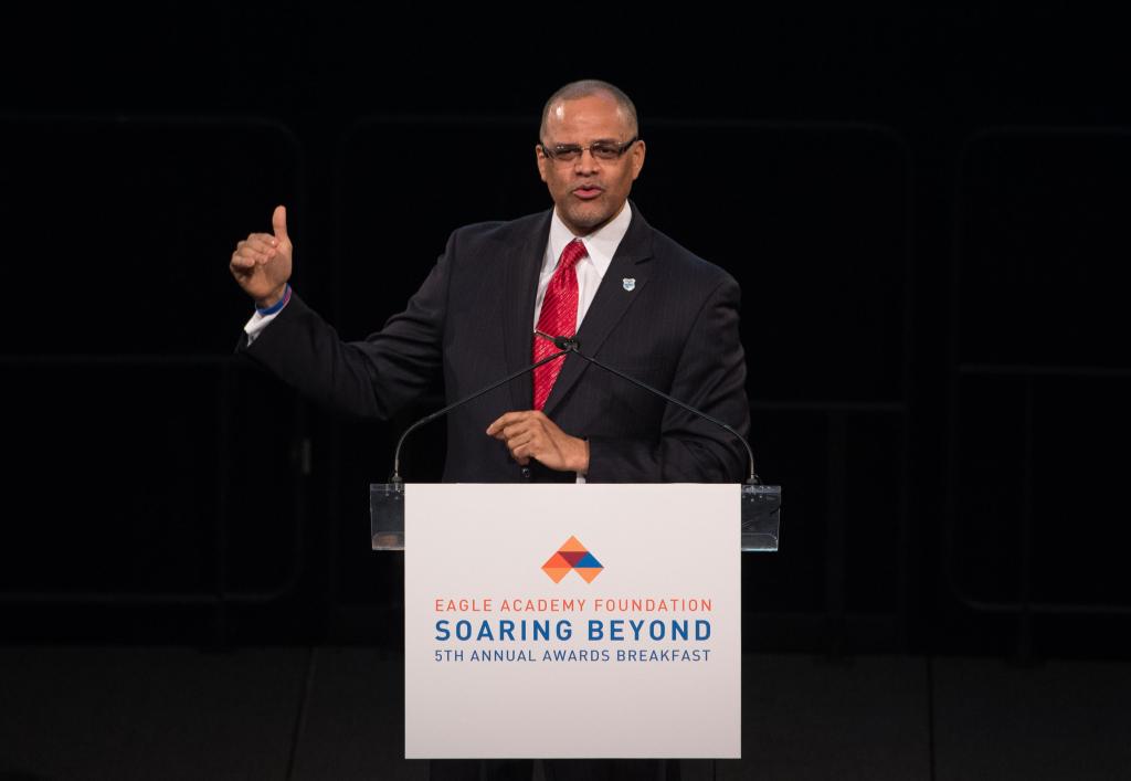 Coaches believe ex-Chancellor David Banks, seen here in a dark suit speaking at a podium, pulled strings to give Eagle Academy in Brooklyn the $4 million refurbished football field.