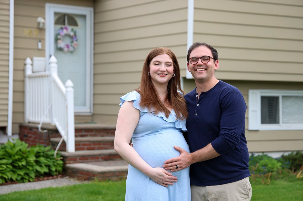 Pregnant Allie and Vinny Frazzetto standing outside their new home.