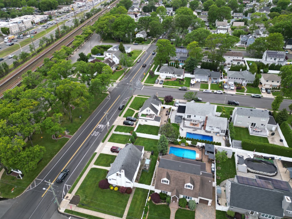 Aerial view of Massapequa Park, NY, showing houses, streets, and a train line.
