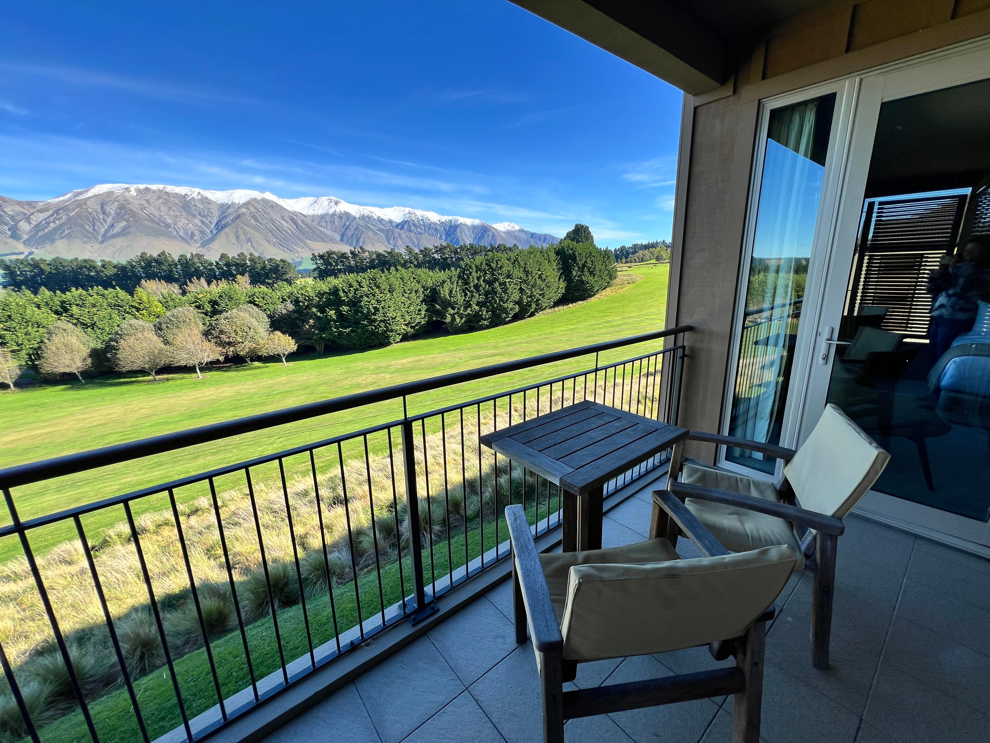 Balcony with two chairs, table, views of mountains and trees