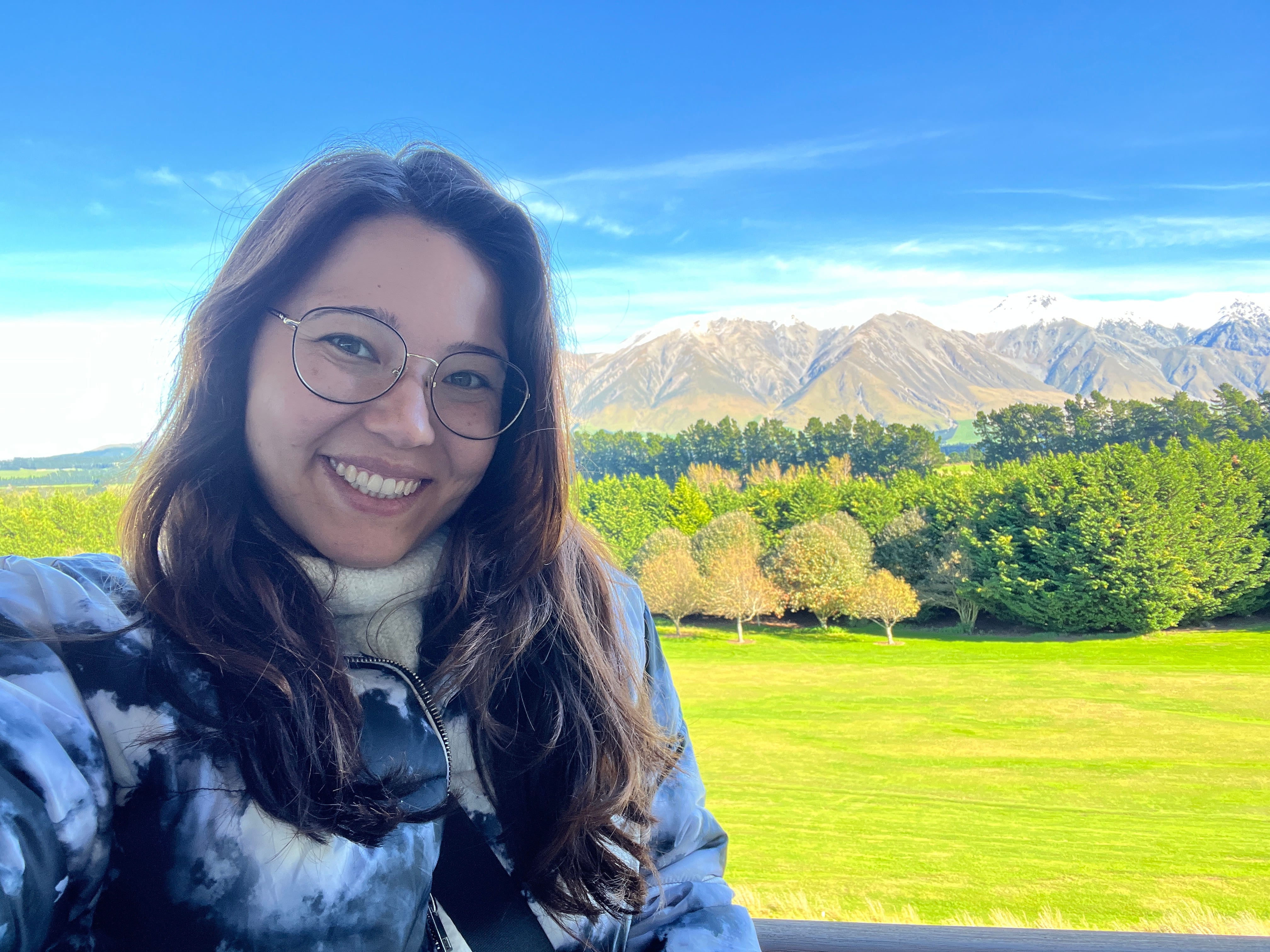 Author Ashley Probst smiling in front of mountains, trees