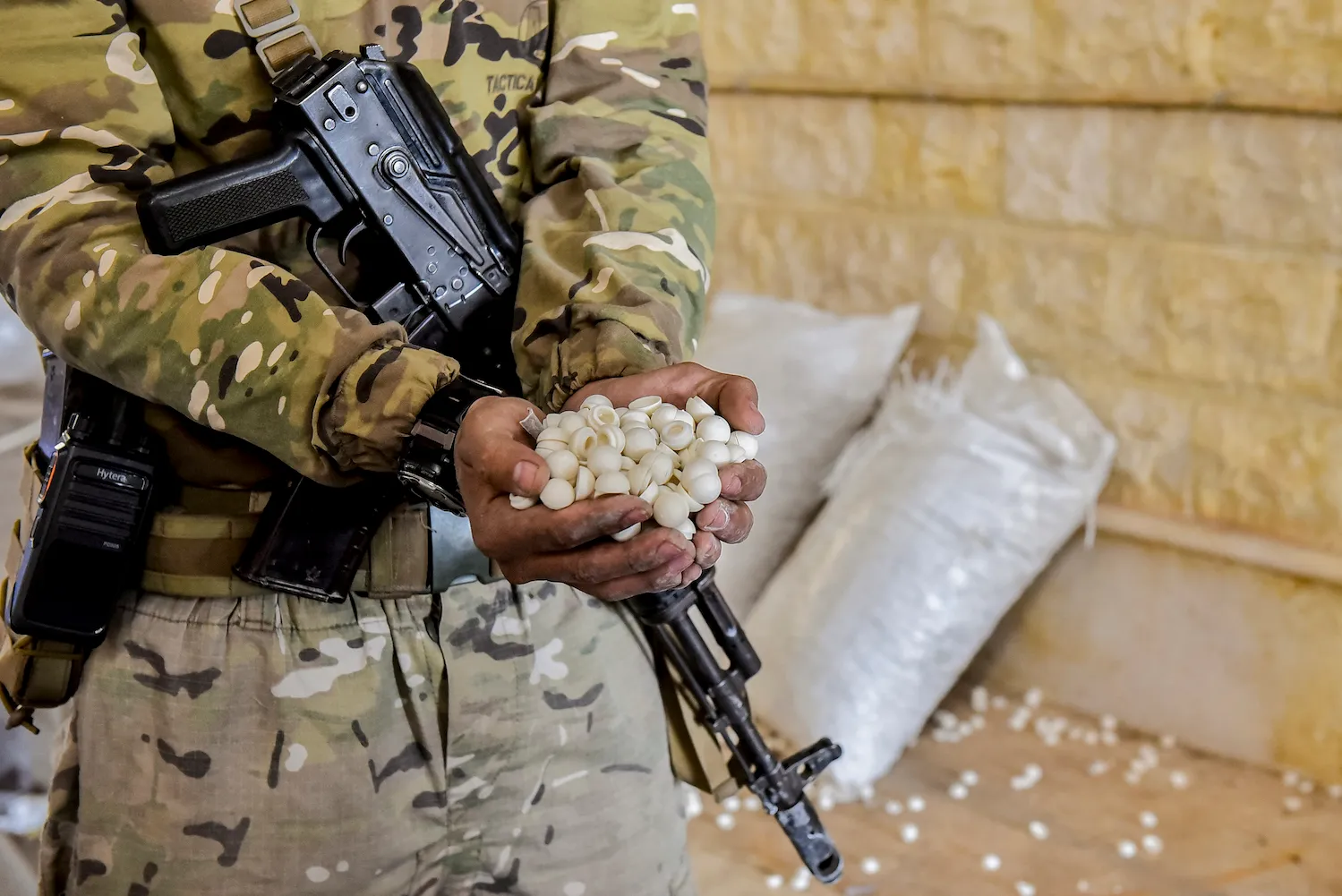 A soldier holds a handful of pills.
