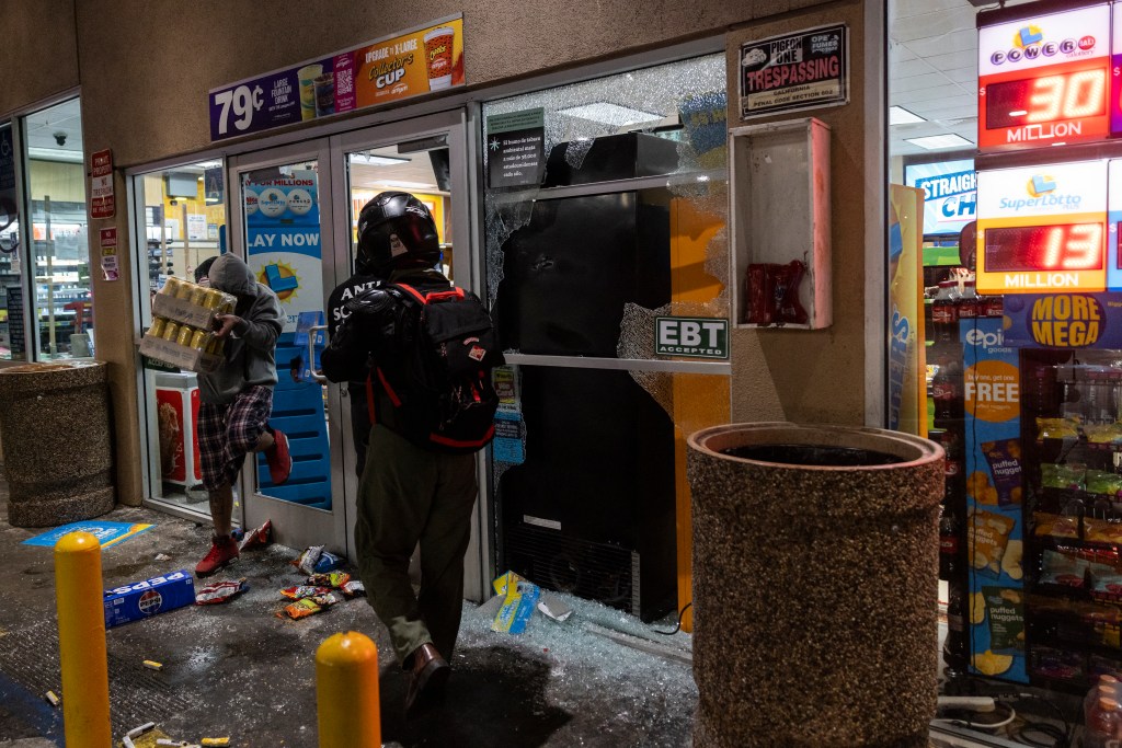 Looters breaking into a gas station during a protest.