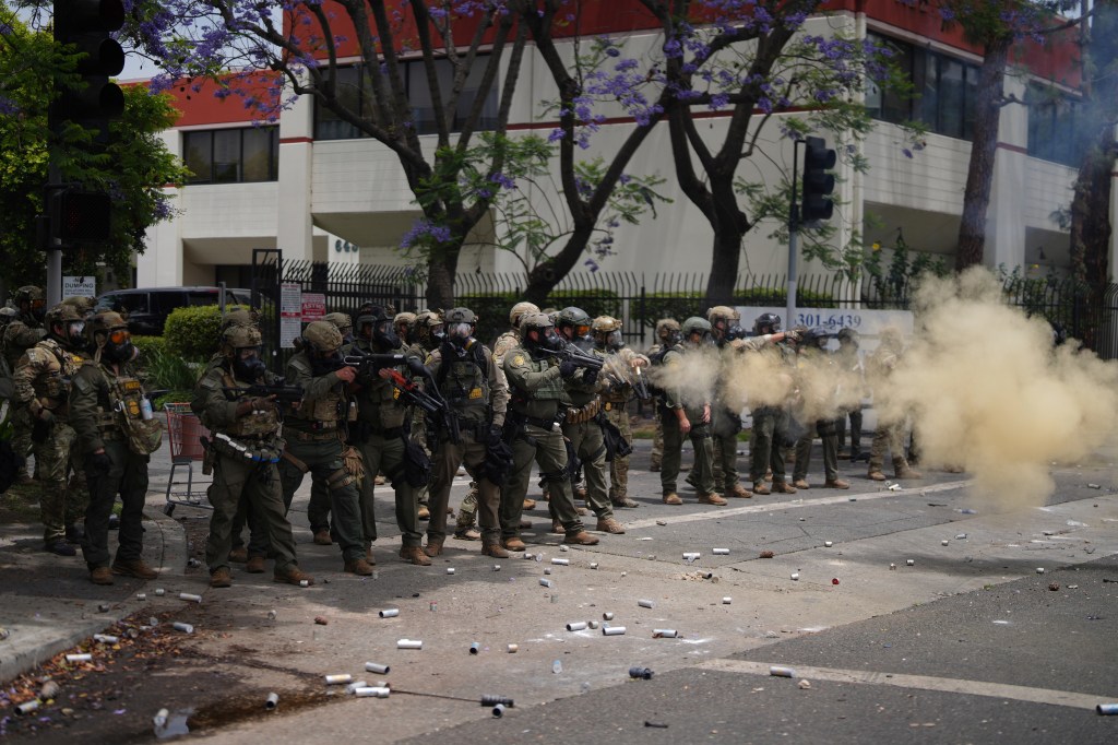 Law enforcement officers in riot gear firing tear gas during a demonstration.