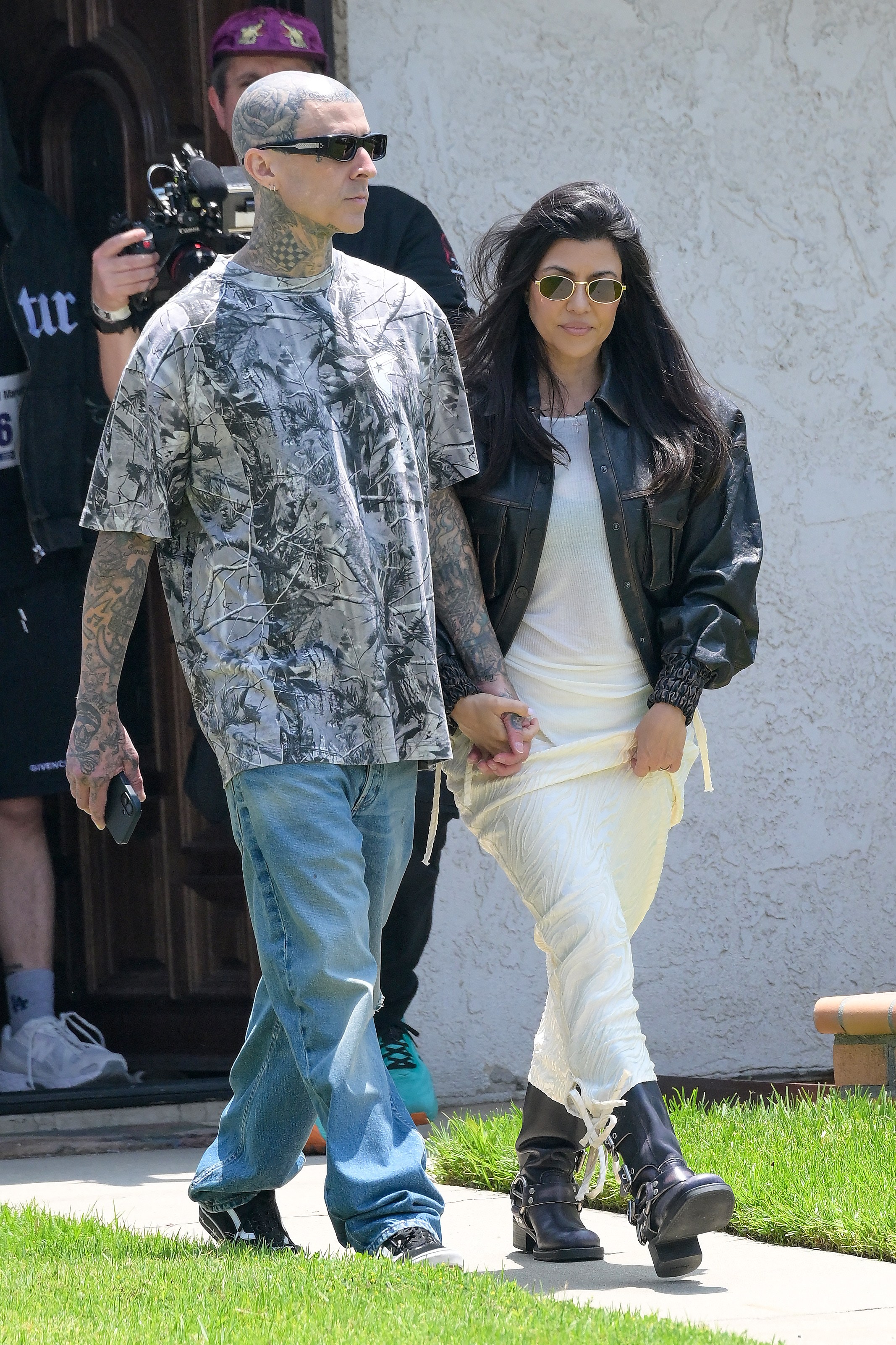 Kourtney Kardashian and Travis Barker walk hand in hand as they visit his father's house after Travis had a street named after him. 