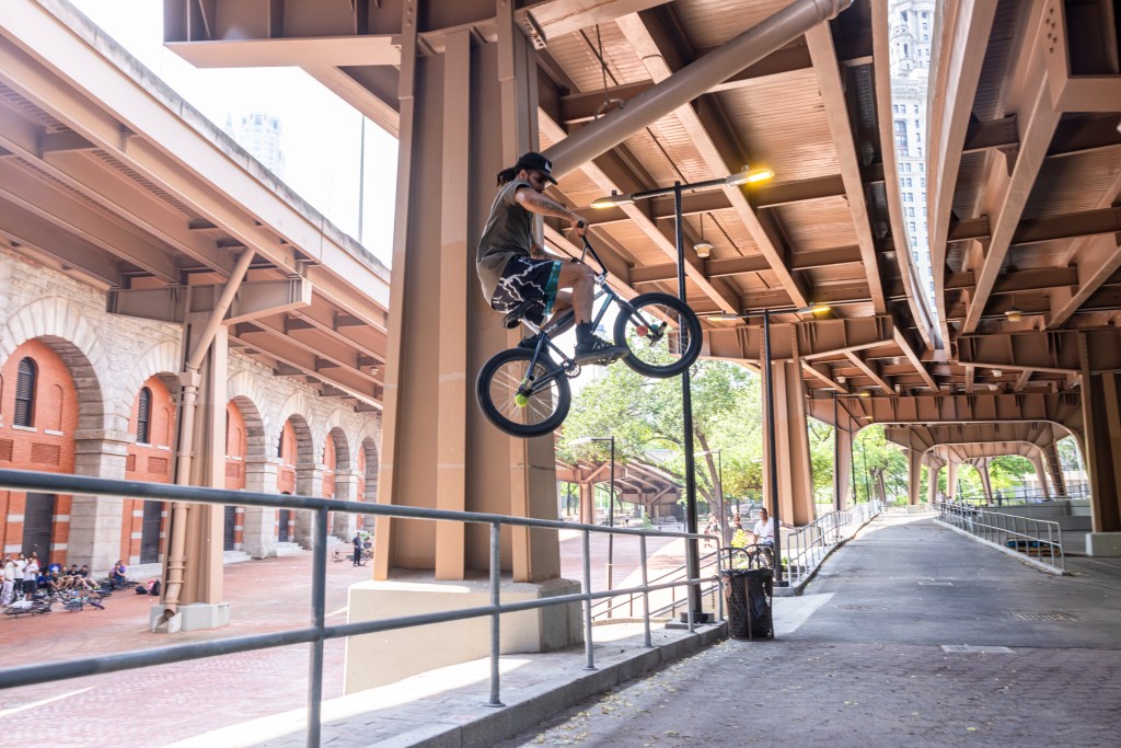BMX rider performing a trick under a bridge.
