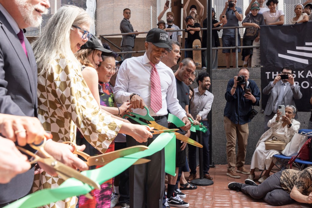 Group of people cutting a green ribbon at a ribbon-cutting ceremony.