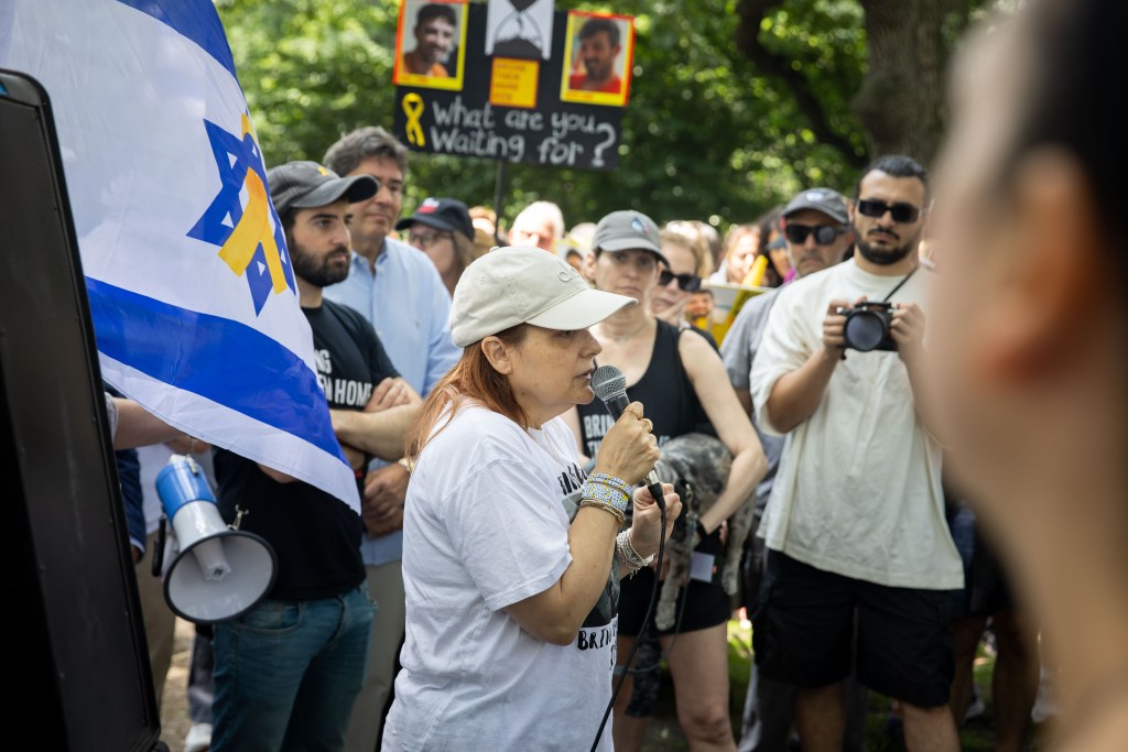 A woman speaks into a microphone at a rally in support of hostages held in Israel.