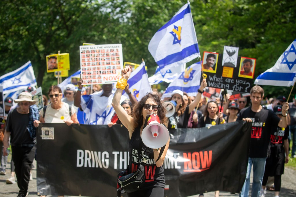 Protestors march in Central Park, NYC, holding signs and Israeli flags, demanding the release of hostages.