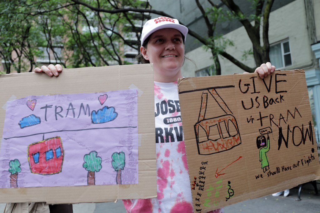 Person holding signs advocating for tram restoration.