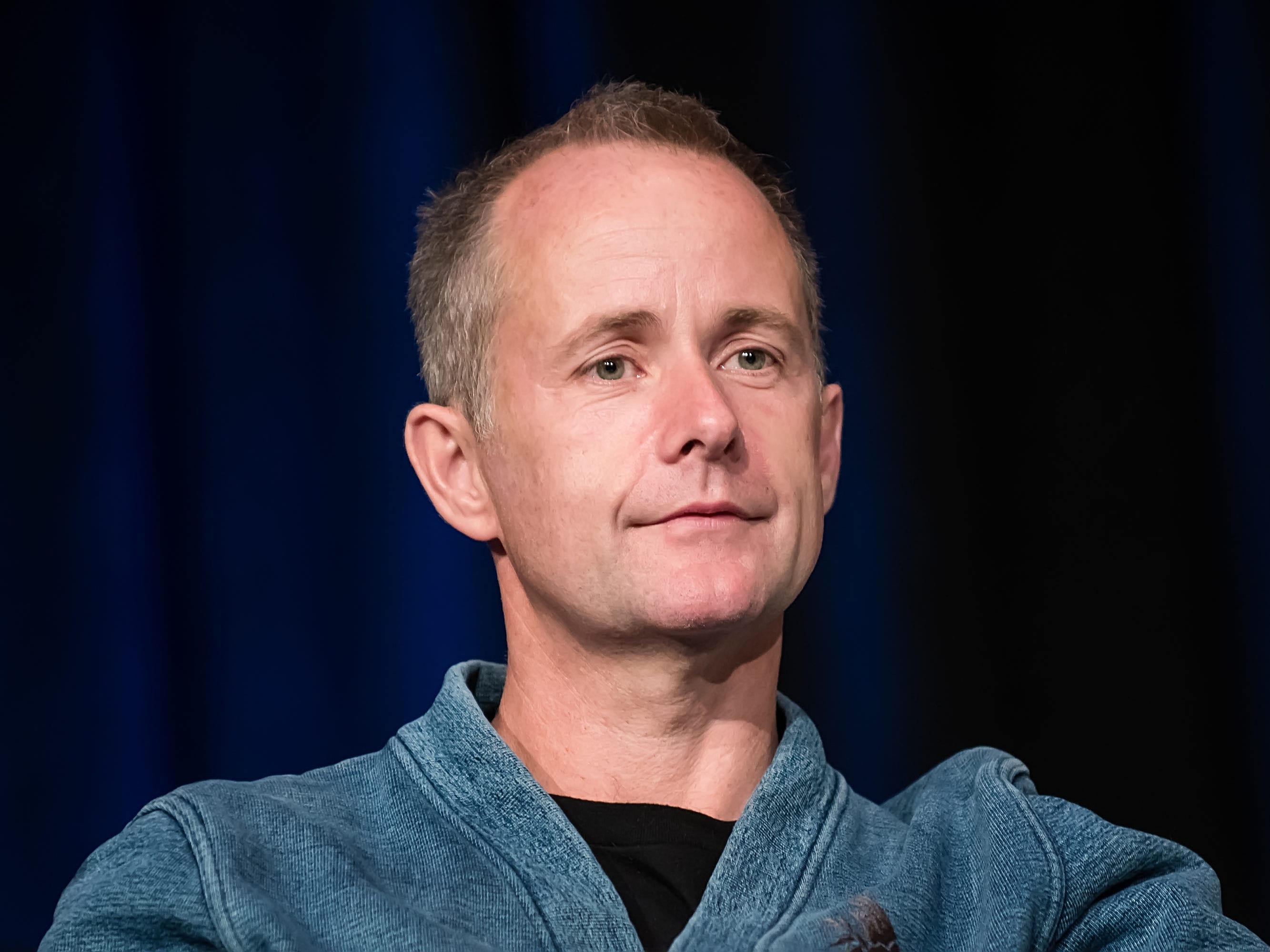billy boyd wearing a light blue jacket in front of a dark blue curtain