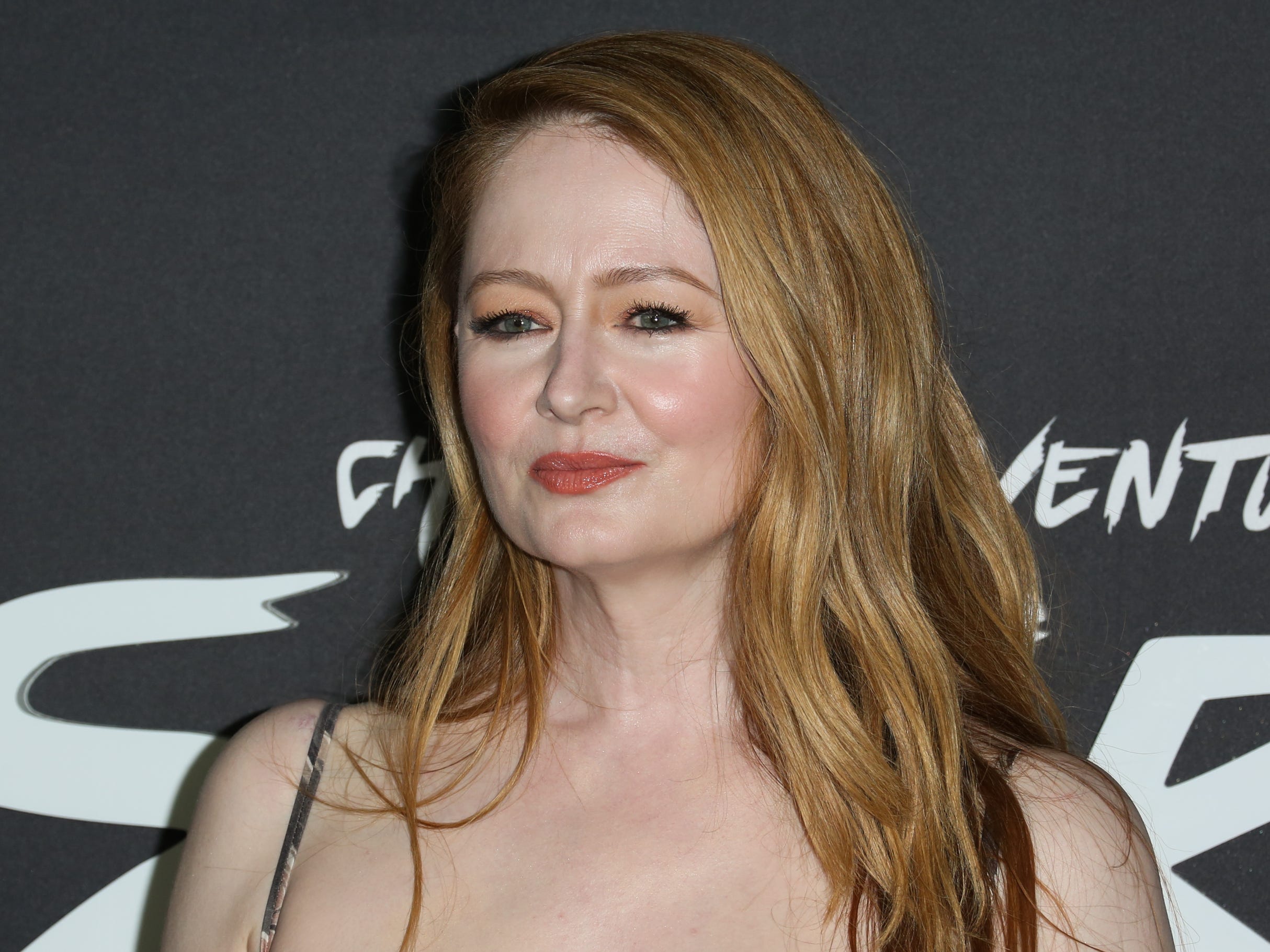 Miranda Otto standing in front of a black background