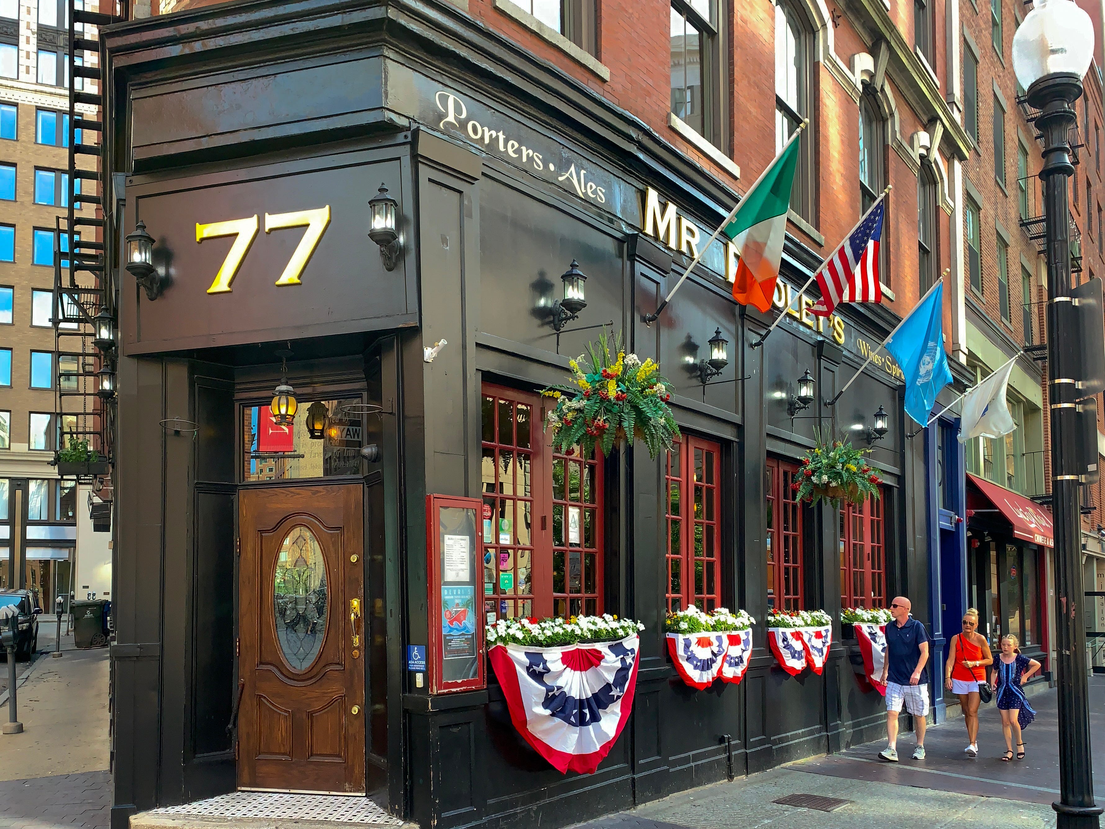 A man, a woman, and a young girl walk past Mr. Dooley's Irish Pub in Boston.