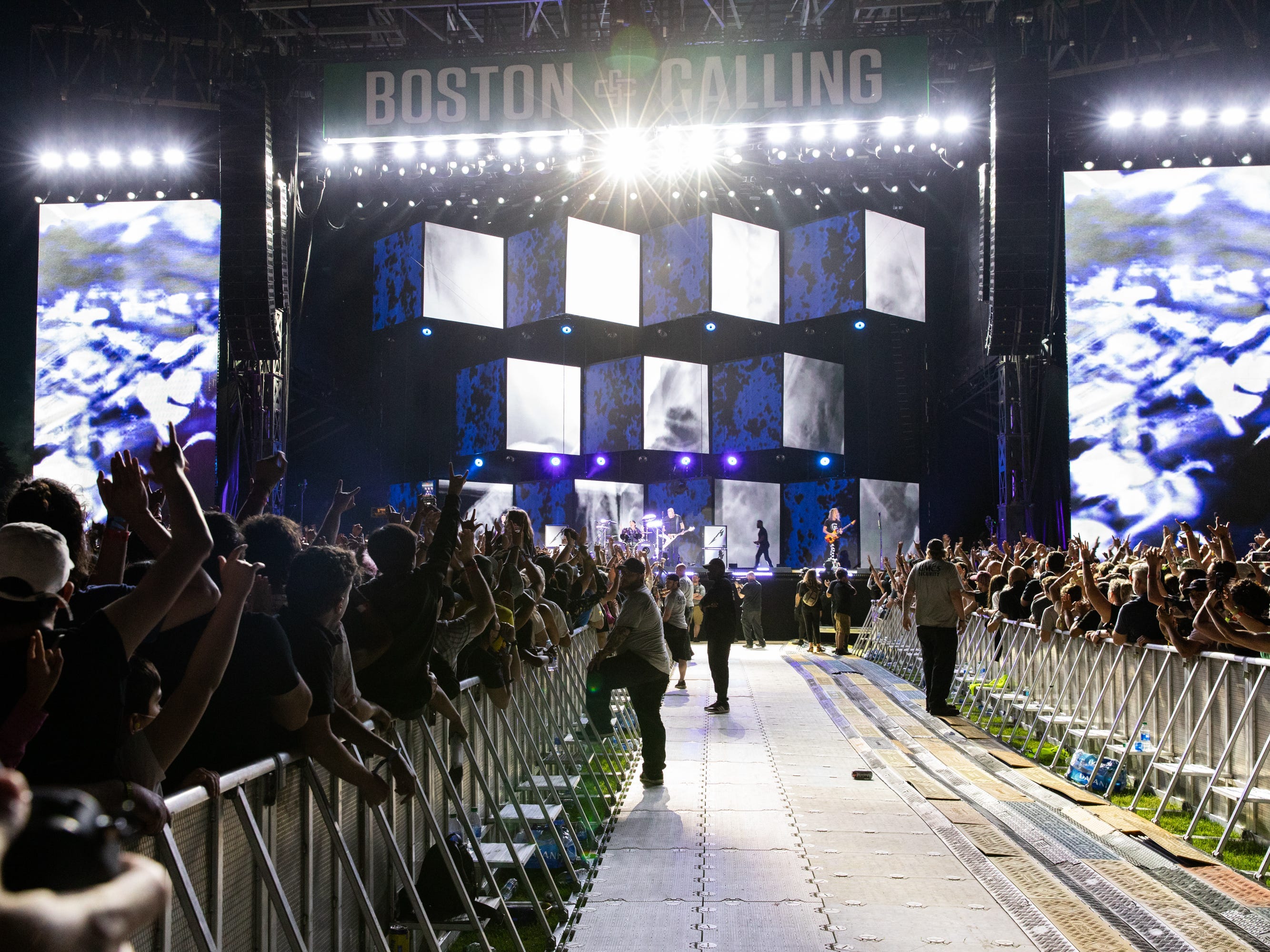 Two barricades of fans with a walkway in between watch a concert at the Boston Calling festival.