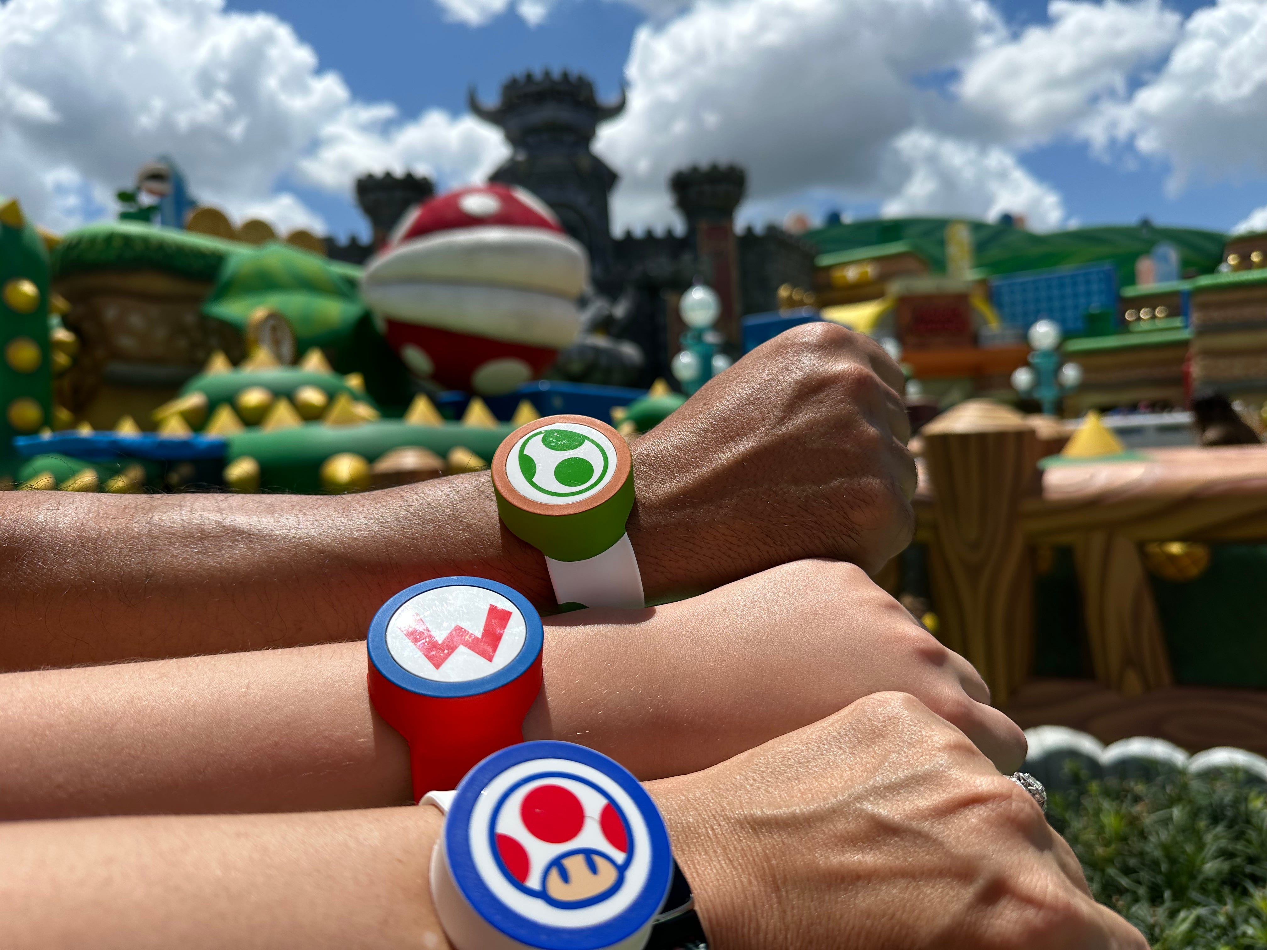 Nintendo power bands on three peoples' wrists at Epic Universe