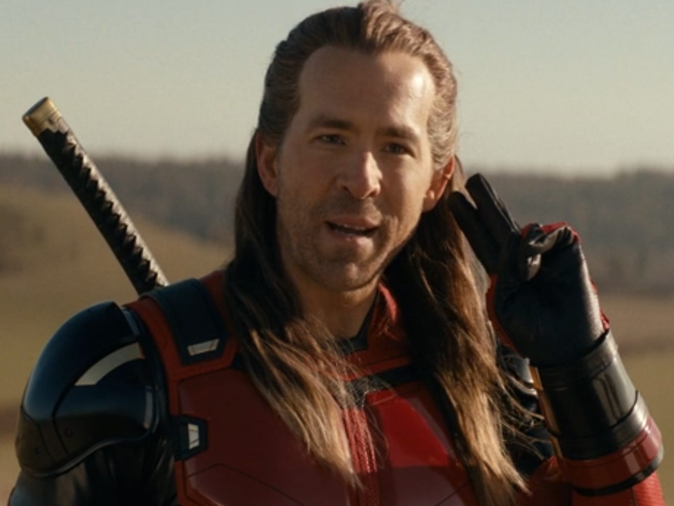 A screengrab from "Deadpool & Wolverine" showing Ryan Reynolds with long hair.